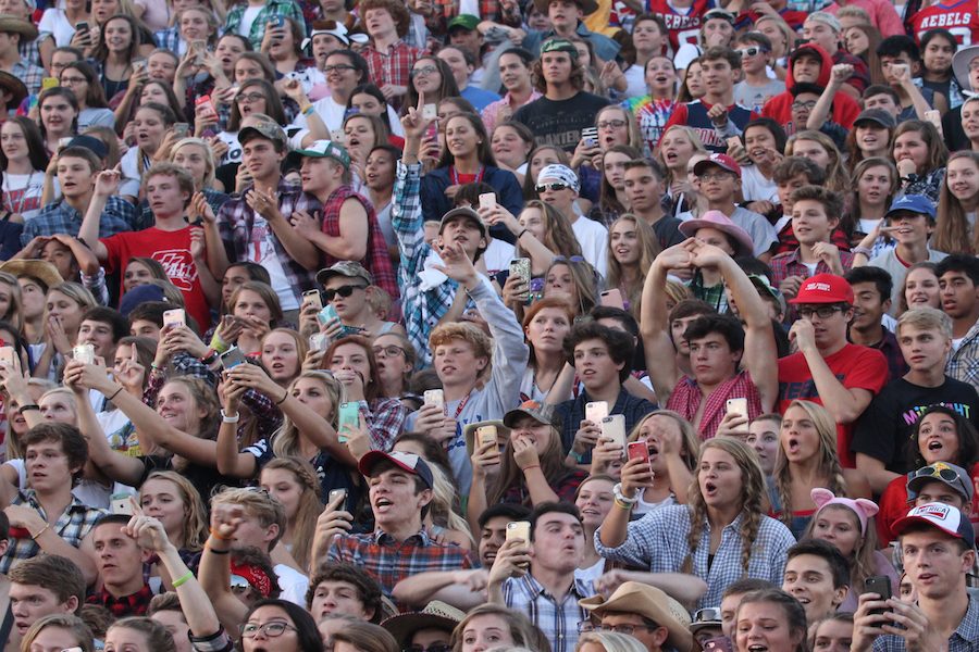 PHONE CRAZE: Members of the student section at a football game pull out their phone to record the results of the Chick-fil-A challenge. While phones can serve as a distraction, teens have also made the most of them in a positive way.