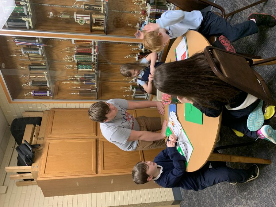 THE LION AND HIS CUBS: Junior Ben Bailey helps young students with their homework at St. Mark. This is one of his many duties that he has as a St. Mark aftercare worker.
