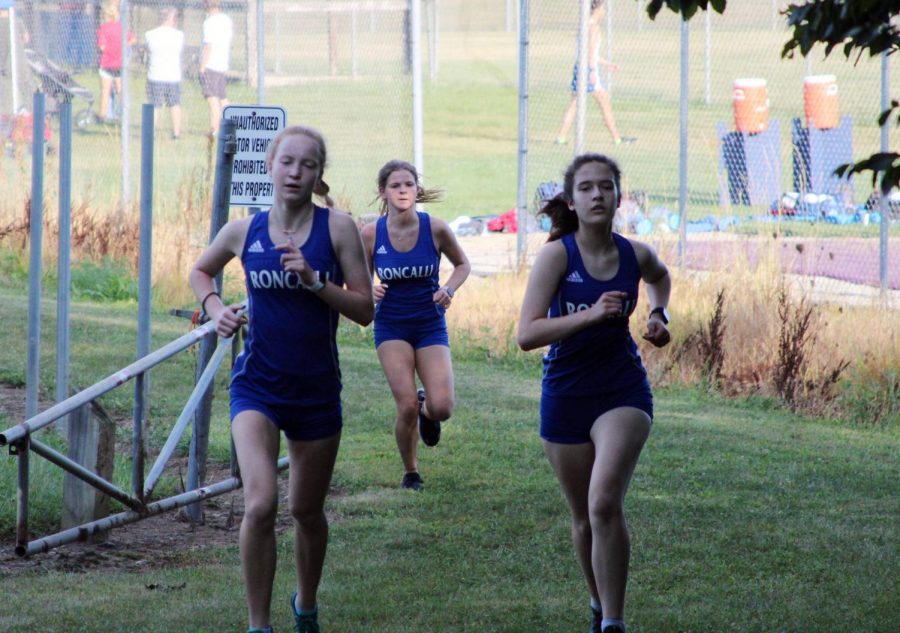 Juniors Amelia Warner and Sara McGraw run with sophomore Sophia Ramsey at a cross country meet