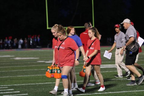 TRAINERS ON THE TURF: Freshman Gianna Miller, Mary Renshaw, Callie Elrod and senior Natalie Mullin walk back to the sidelines after refreshing the football team, a typical half-time necessity. The Royals defeated Brebuf at this years Homecoming game, 28 to 10.