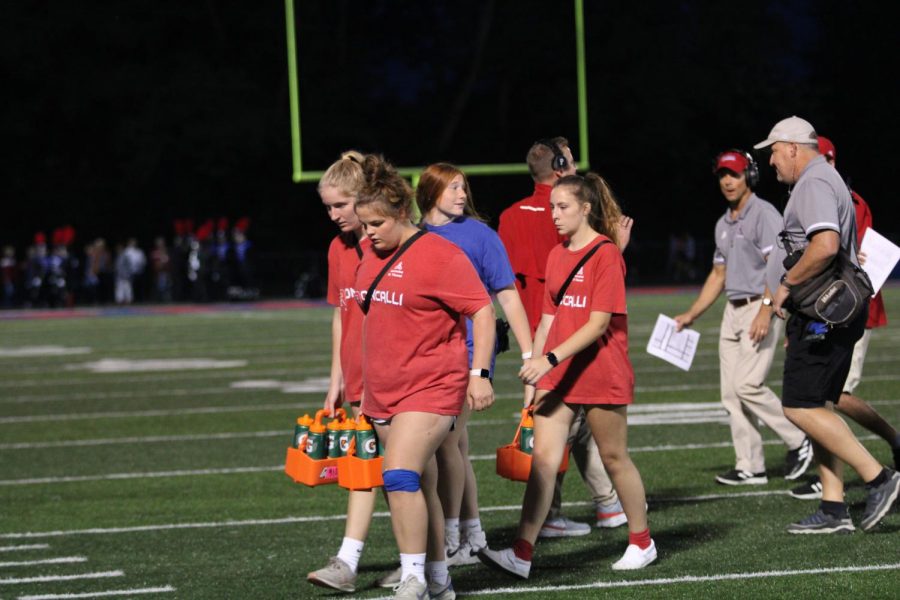 TRAINERS ON THE TURF: Freshman Gianna Miller, Mary Renshaw, Callie Elrod and senior Natalie Mullin walk back to the sidelines after refreshing the football team, a typical half-time necessity. The Royals defeated Brebuf at this year's Homecoming game, 28 to 10.
