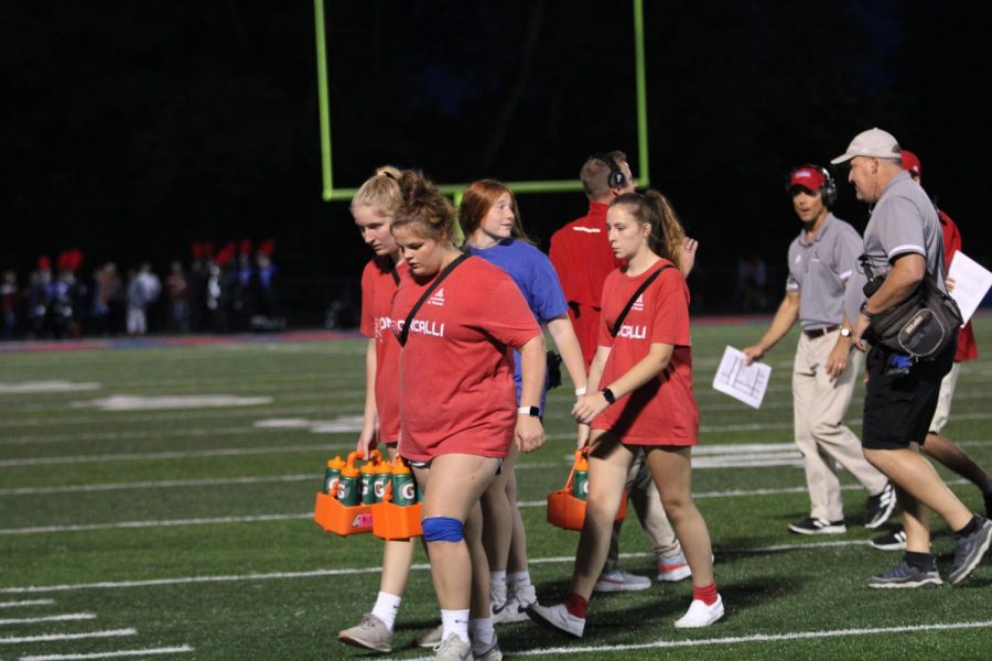 TRAINERS+ON+THE+TURF%3A+Freshman+Gianna+Miller%2C+Mary+Renshaw%2C+Callie+Elrod+and+senior+Natalie+Mullin+walk+back+to+the+sidelines+after+refreshing+the+football+team%2C+a+typical+half-time+necessity.+The+Royals+defeated+Brebuf+at+this+years+Homecoming+game%2C+28+to+10.