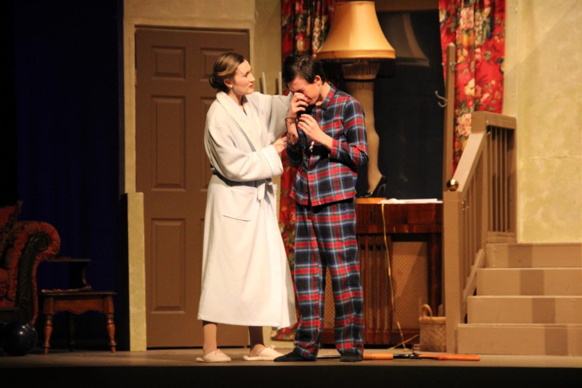 “The mother, played by Junior Molly Resler, comforts Ralphie, freshman J.P Miller, after he shoots his eye out playing with his new toy gun.” 
