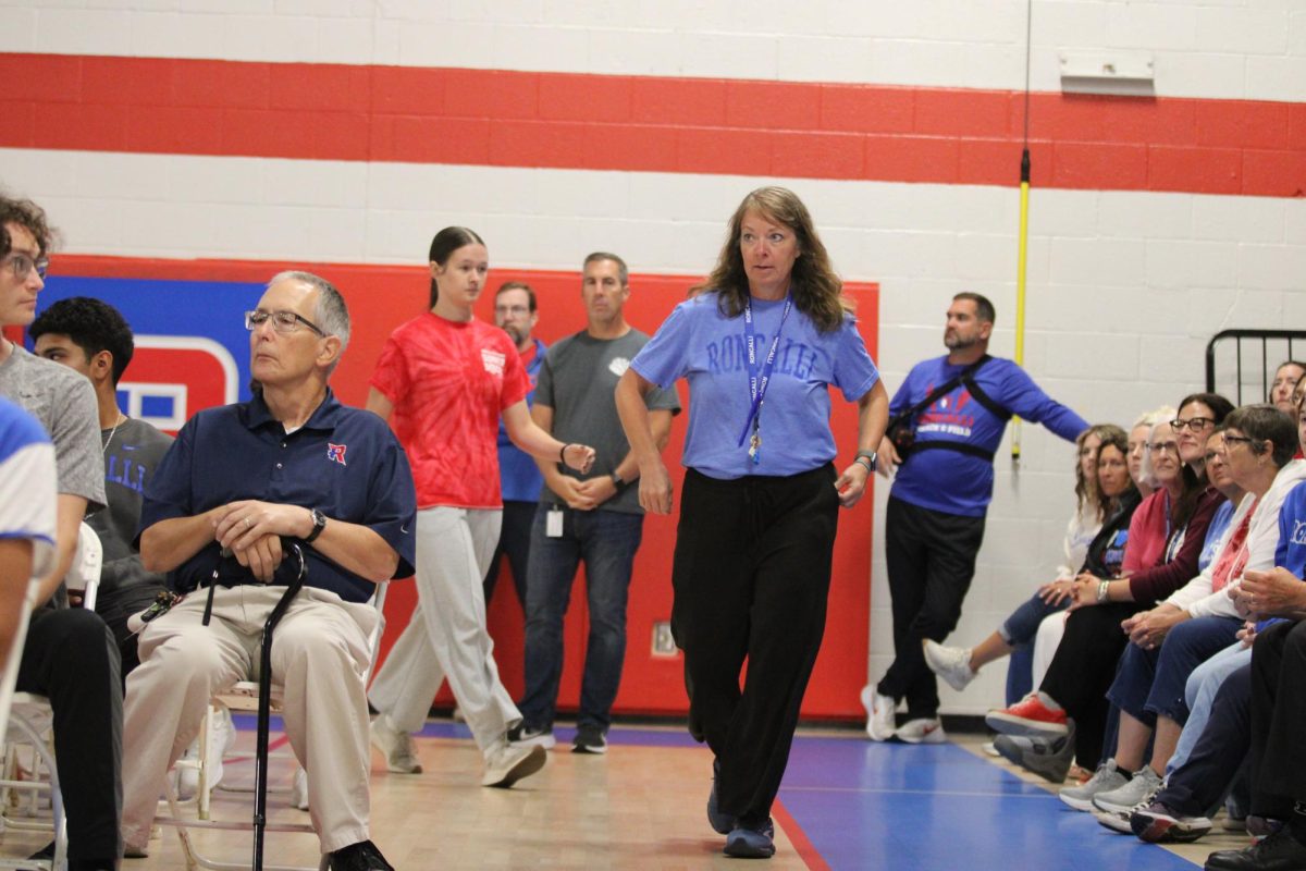 Ms. Kathy Douglass is pictured walking toward the podium during Mrs. Beth Reel’s "new teacher" highlight at opening assembly.
