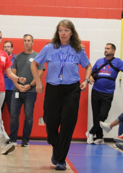 Ms. Kathy Douglass is pictured walking toward the podium during Mrs. Beth Reel’s "new teacher" highlight at opening assembly.