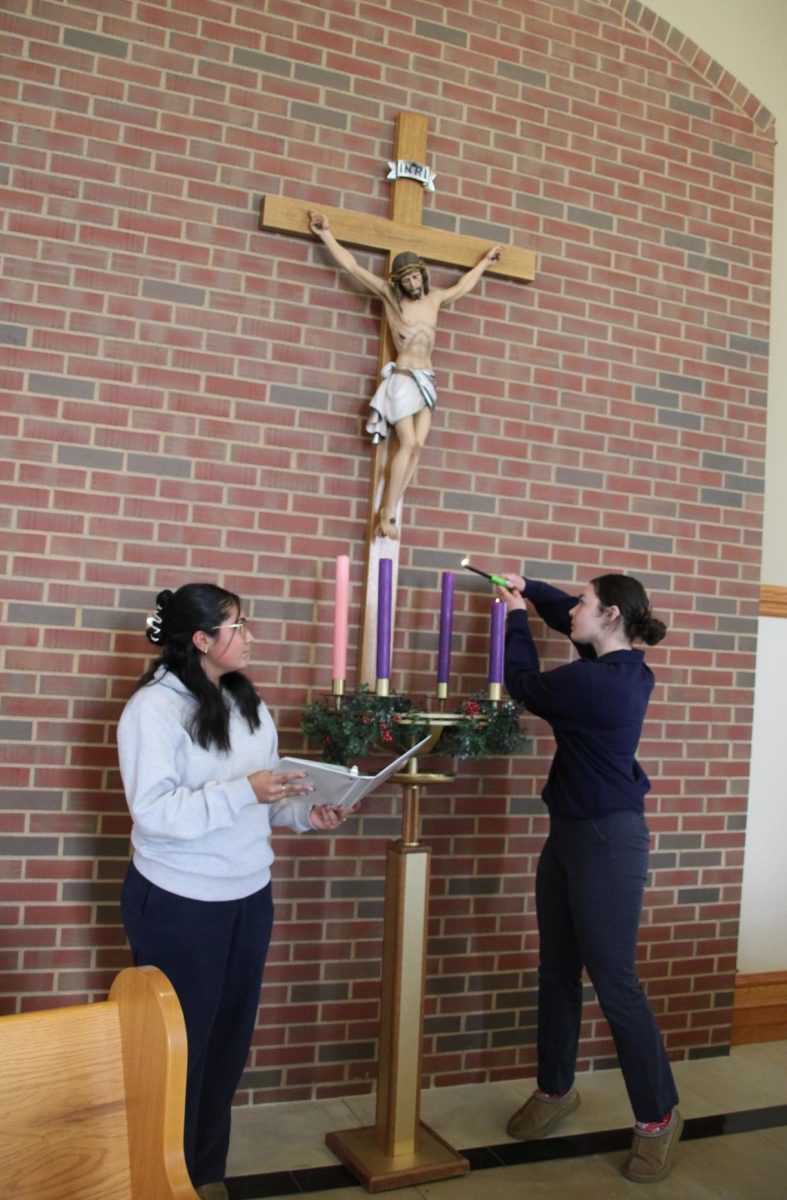Leading Advent all-school prayer, junior Ella Holtz lights the Advent wreath candles as junior Fatima Soberanes-Aguayo reads a reflection and prayer. The prayer and lighting of the wreath were live streamed every Monday during morning announcements in Advent. 
