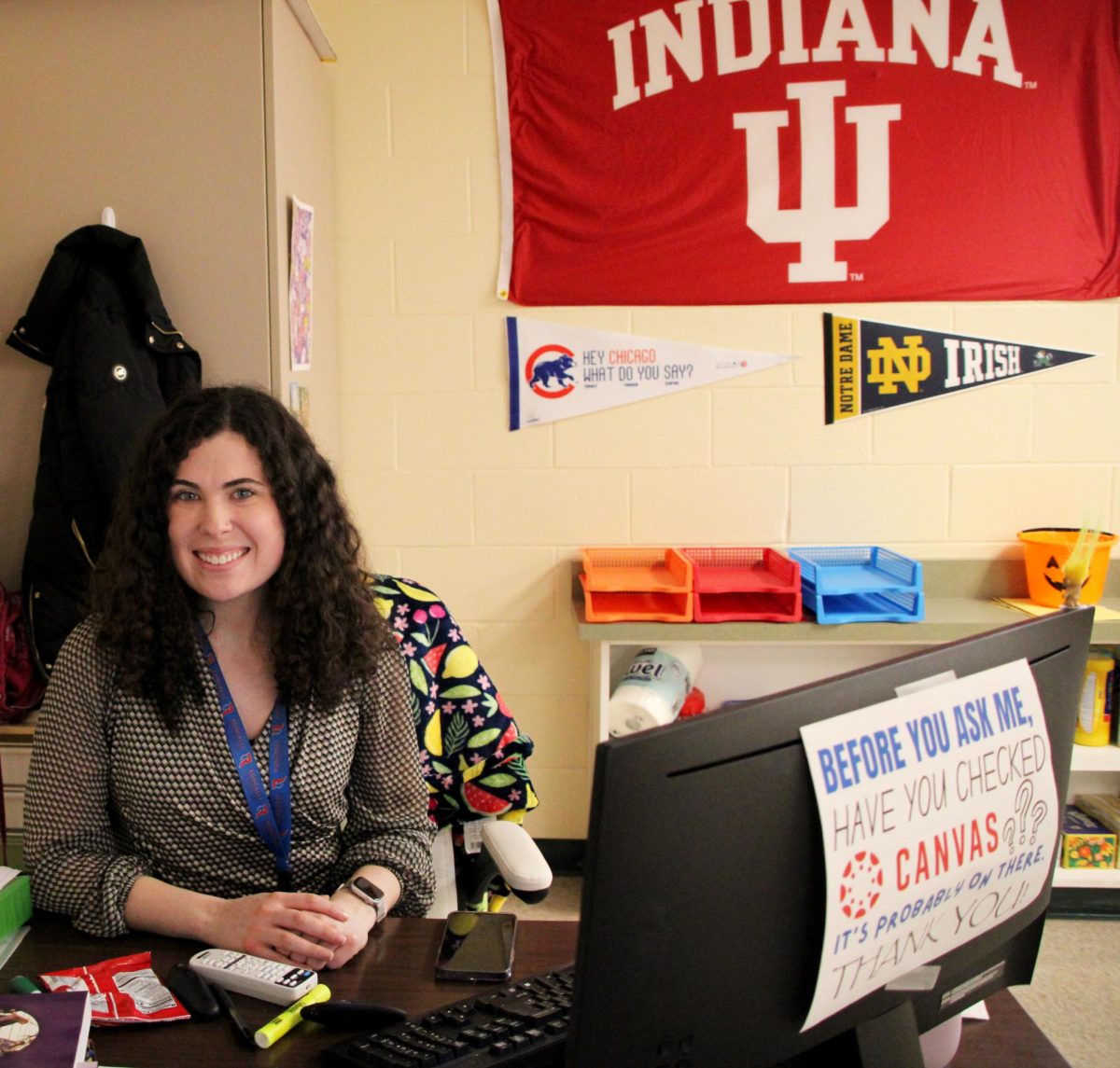Ms. Grace Field works at her desk as a first-year theology teacher. Field completed her undergraduate degree at Indiana University and is currently finishing her masters at Notre Dame, with both flags featured in the background.